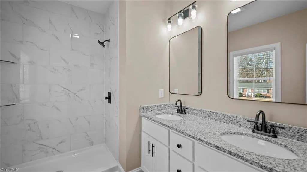 Bathroom with double granite vanity and marble tile shower