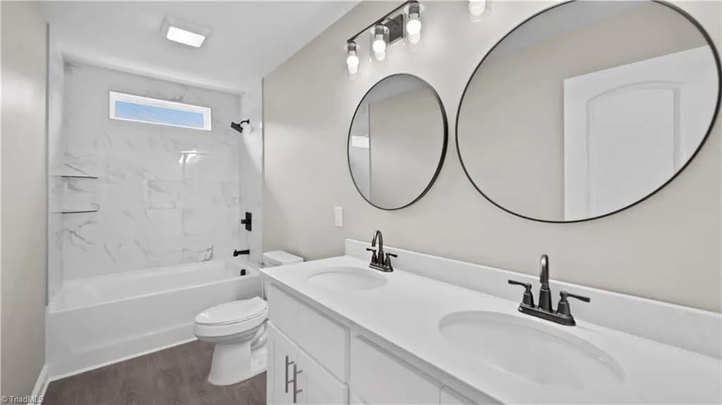 Primary bathroom with double vanity and marble tub surround