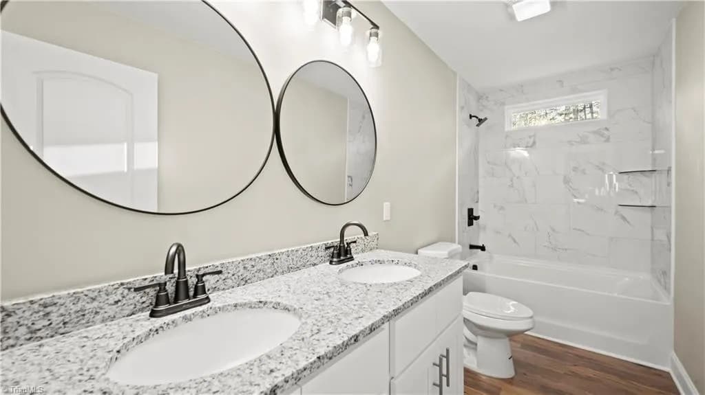 Primary bathroom with double granite vanity and marble tub surround