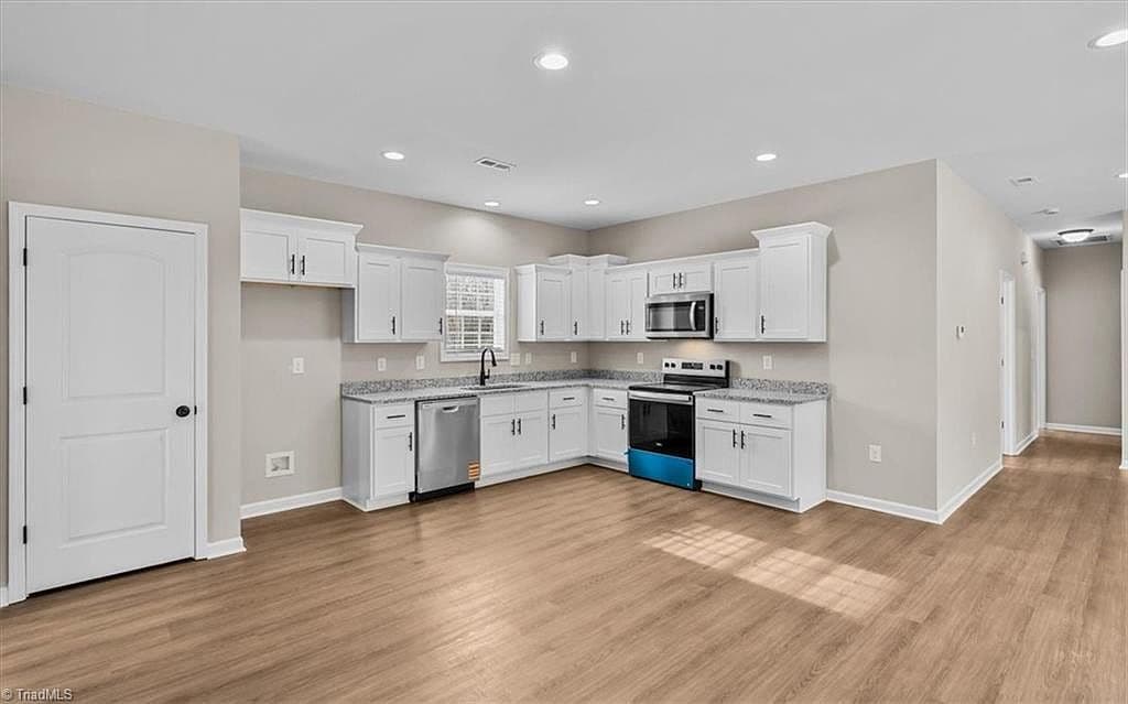 Open kitchen with white cabinets and granite